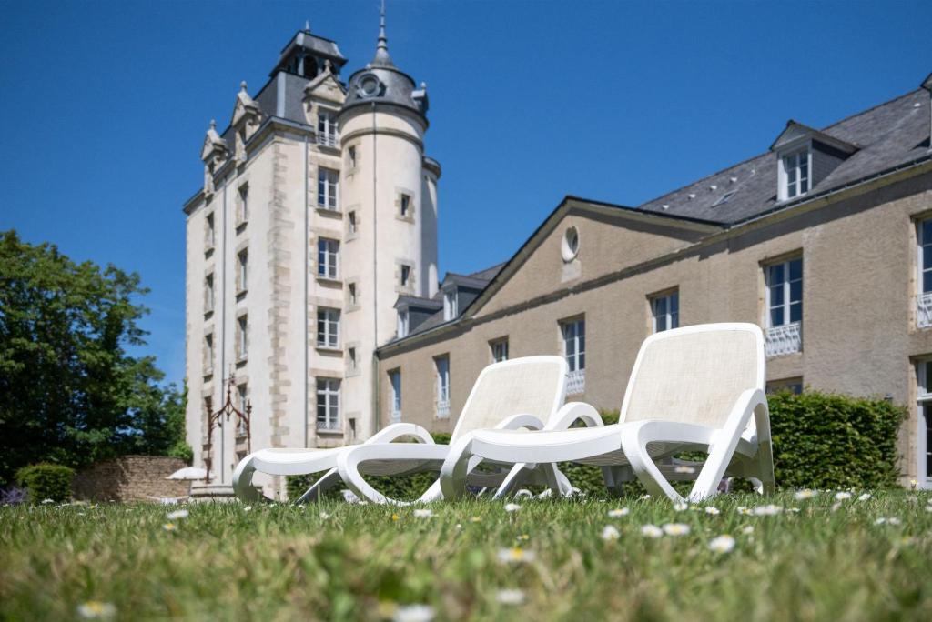 three white chairs sitting in the grass in front of a building at Résidence Odalys Le Château de Kéravéon in Erdeven