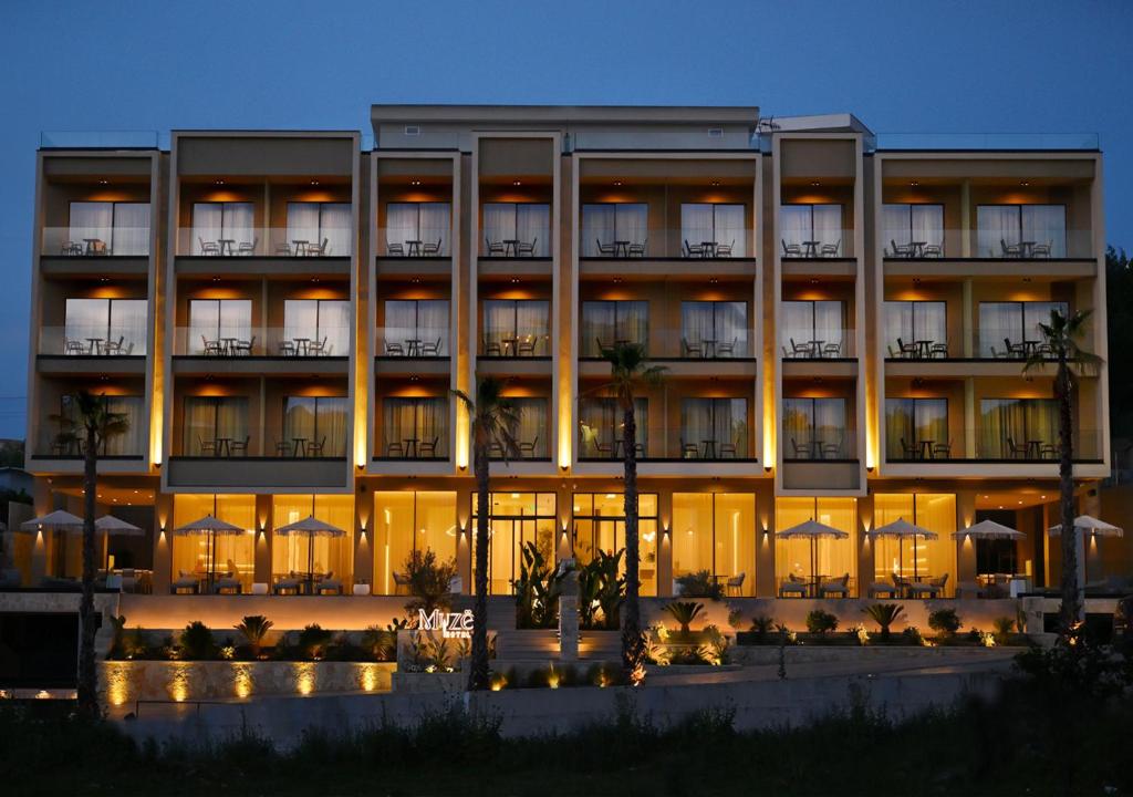 a large hotel with a lit up facade at night at Muze Hotel in Ksamil