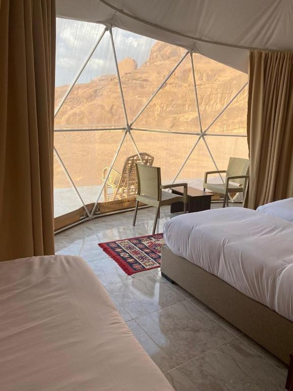 a room with two beds and a view of the desert at Desert Hello Camp in Wadi Rum