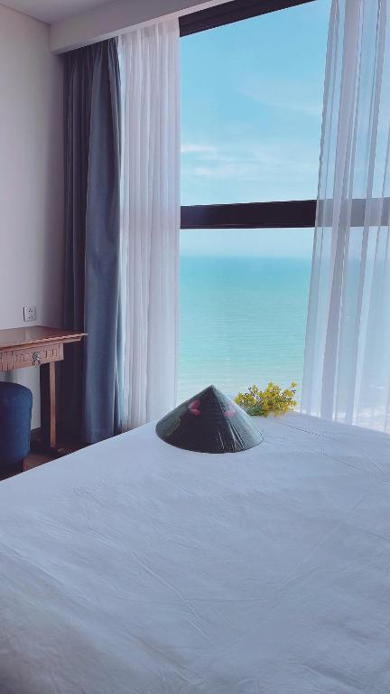 a bedroom with a bed and a large window at APEC Mandala Mũi Né Official - Diễm Phạm Travel in Phan Thiet