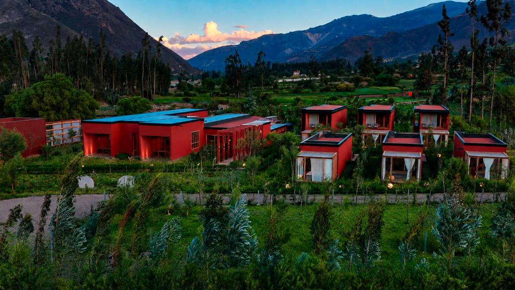 a row of red houses in a field with mountains at Viscas Hotel Luxury Resort & Spa in Pariahuanca