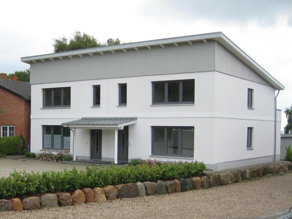 ein weißes Haus mit schwarzen Fenstern in der Unterkunft Ferienwohnung Meeschendorf in Fehmarn