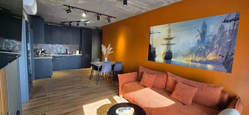 a living room with a couch and a kitchen at Apartament Baltic 13 Mielno in Mielno