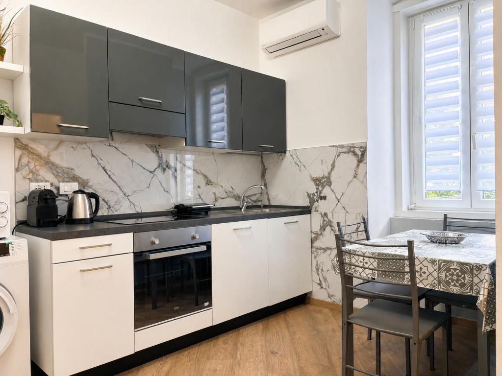 a kitchen with white cabinets and a table at Da Nonno Eddie - tranquillo bilocale - wi-fi - tv - parcheggio vicino in Trieste