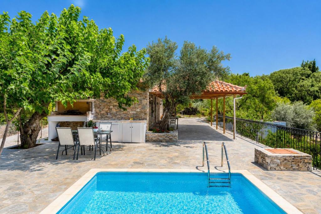 a pool in a backyard with a table and chairs at Oak Tree Cottage in Pefkias