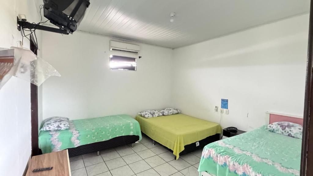 a room with two beds and a tv in it at Pousada Zambaiam in Torto