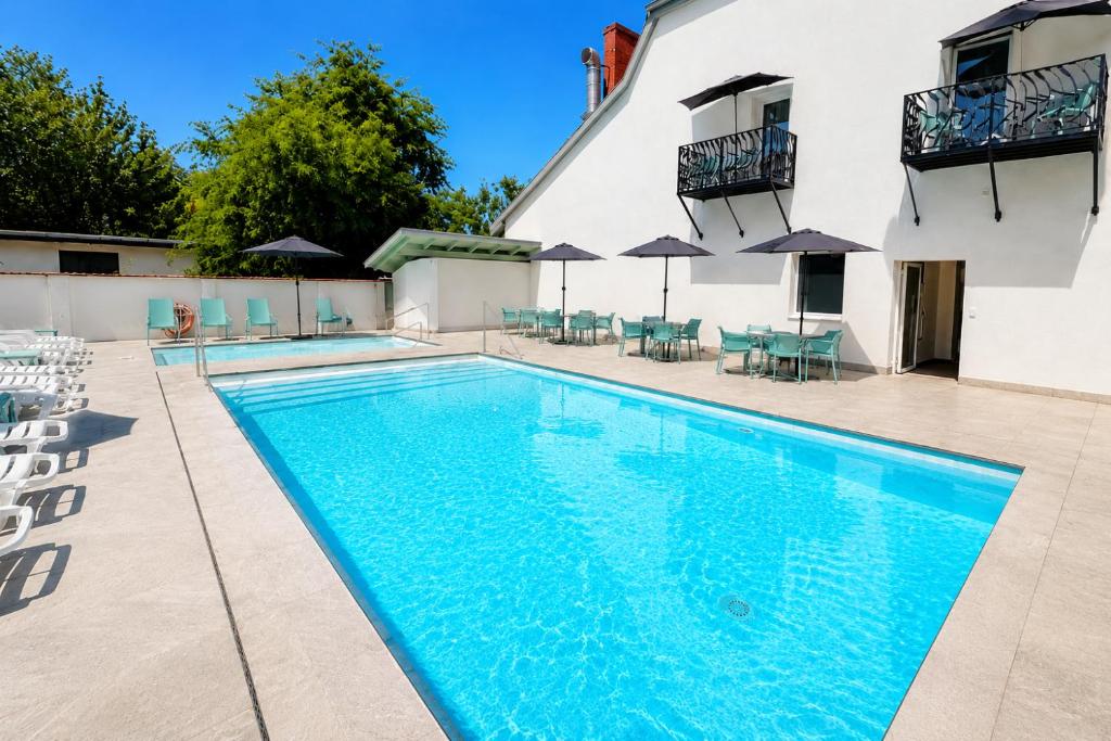 a swimming pool with chairs and umbrellas next to a building at Pater Apartments and Rooms in Siófok