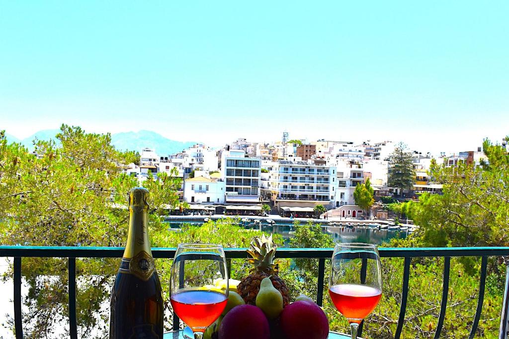 a table with two glasses of wine and fruit on a balcony at Luxury Lake View in Agios Nikolaos