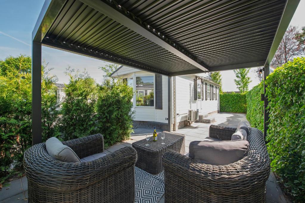 a patio with wicker chairs and tables under a pergola at 80, Midden in de natuur - Airco! in Oisterwijk