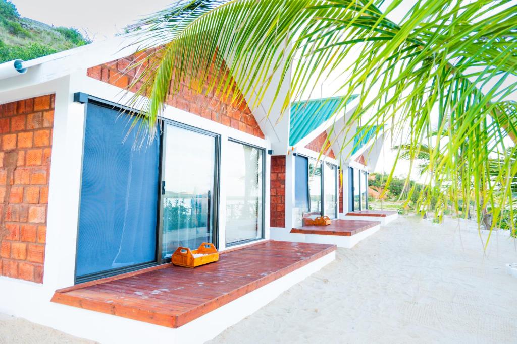 a house with a balcony with windows and a palm tree at Koko Beach - Honeymoon Suite in Vila Praia Do Bilene