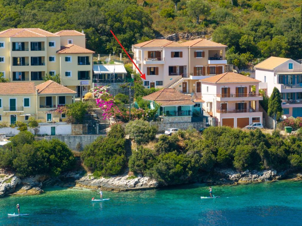 two boats in a body of water with houses at Tassos Cottage Fiskardo in Fiskardo