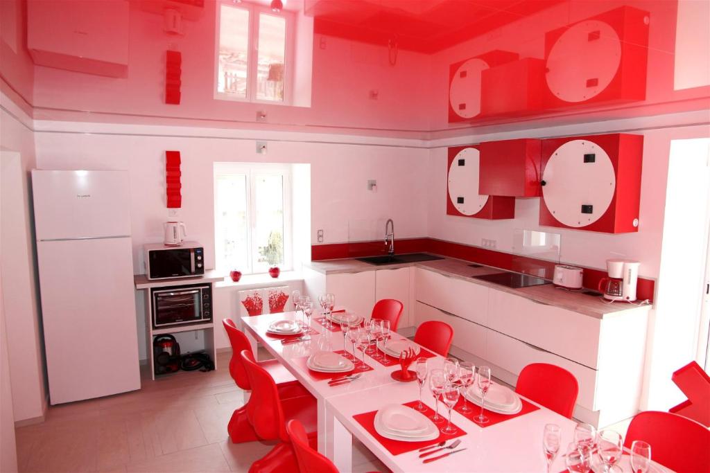 a kitchen with a white table and red chairs at L'inattendu in Les Piards
