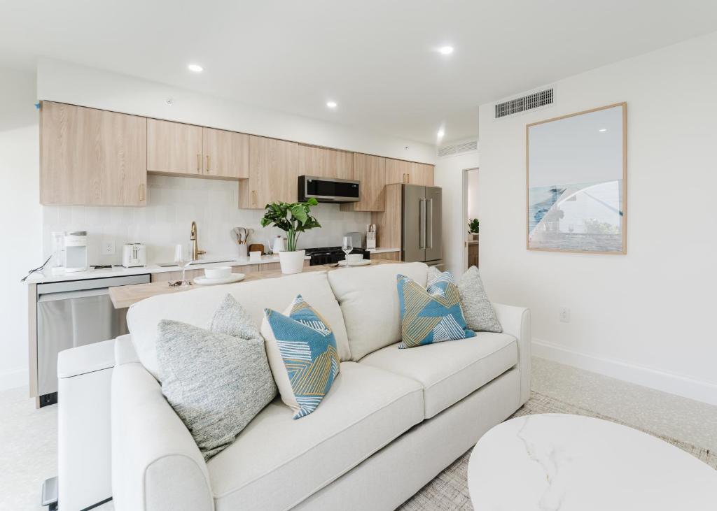 a white living room with a white couch and a kitchen at Casa Coral - Boca Poolside Escape in Boca Raton