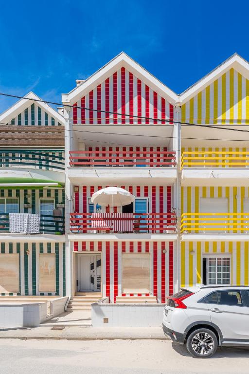 a white car parked in front of a colorful building at Salt & Sand Costa Nova Beach in Costa Nova