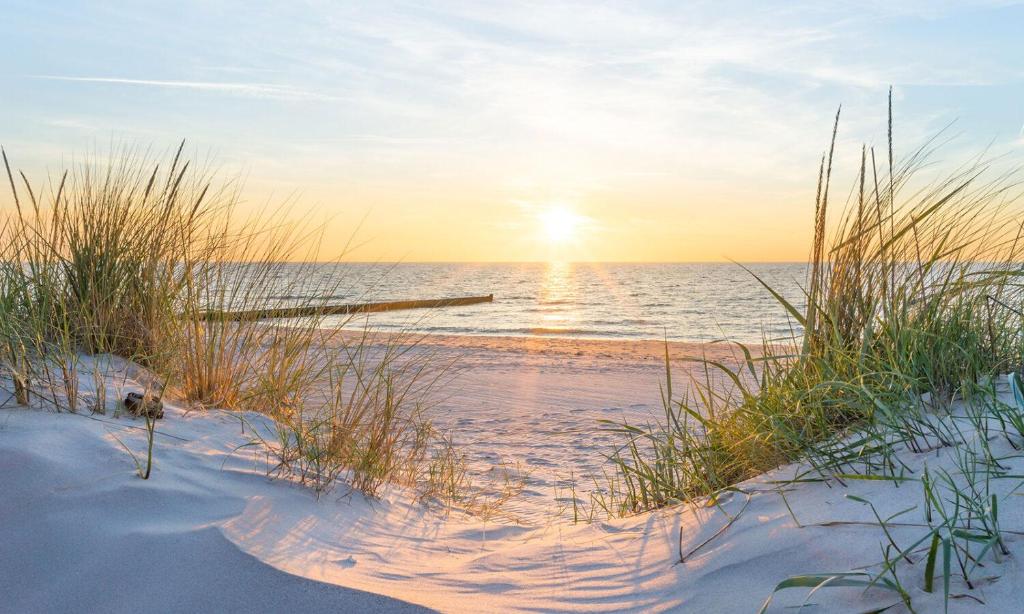 a beach with the sun setting over the water at B5 Jurmala Apartments in Jūrmala