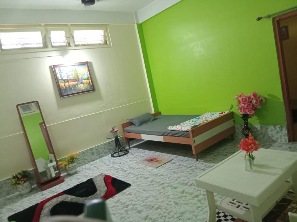 a green room with a bed and a mirror at niribili homestay in Dibrugarh