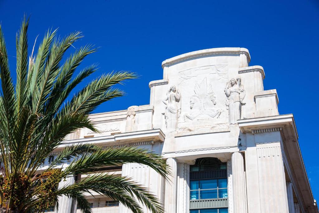 a building with a palm tree in front of it at Hotel Palais de la Mediterranee, in the Unbound Collection by Hyatt in Nice