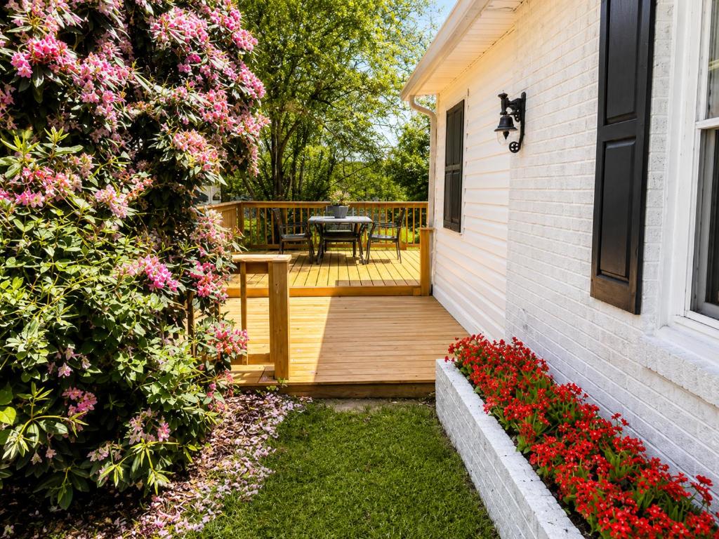 a deck with a table and flowers on a house at Little Elves Overlook in Sparta