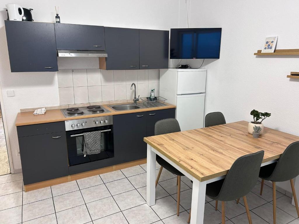 a kitchen with a table and a stove and refrigerator at Hauckwald Apartment 5 in Alzenau