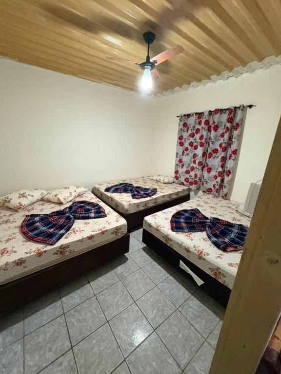 three beds in a room with a ceiling at Casa a 3 minutos da basilica in Aparecida