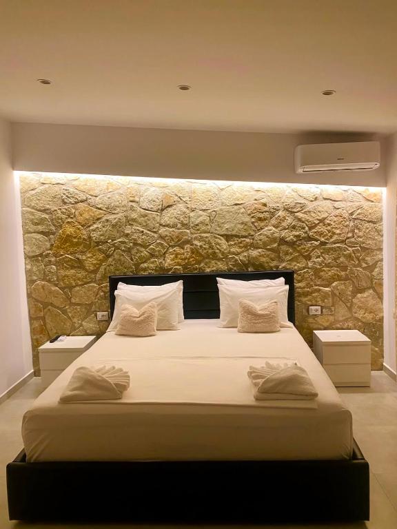 a bedroom with a large bed with a stone wall at Luciano Rooms in Ksamil