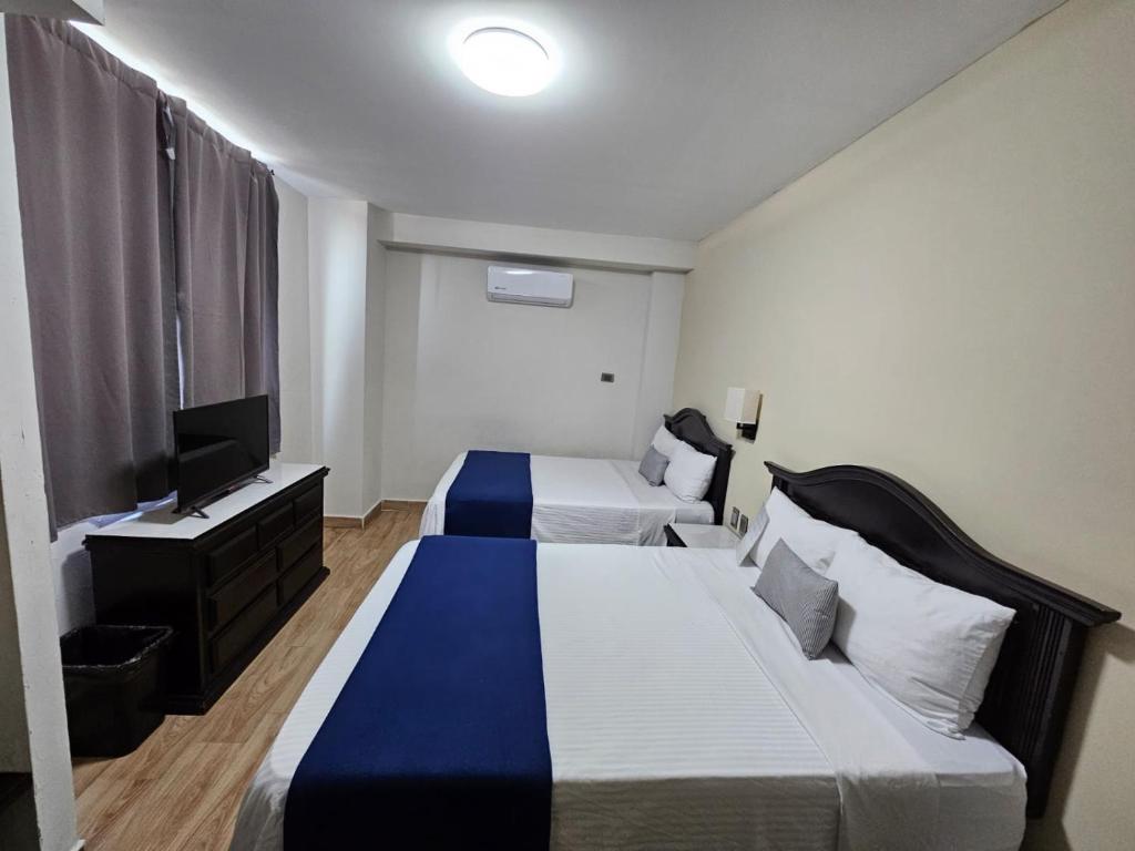 a hotel room with two beds and a flat screen tv at Hotel Plaza del Arco - Monterrey in Monterrey