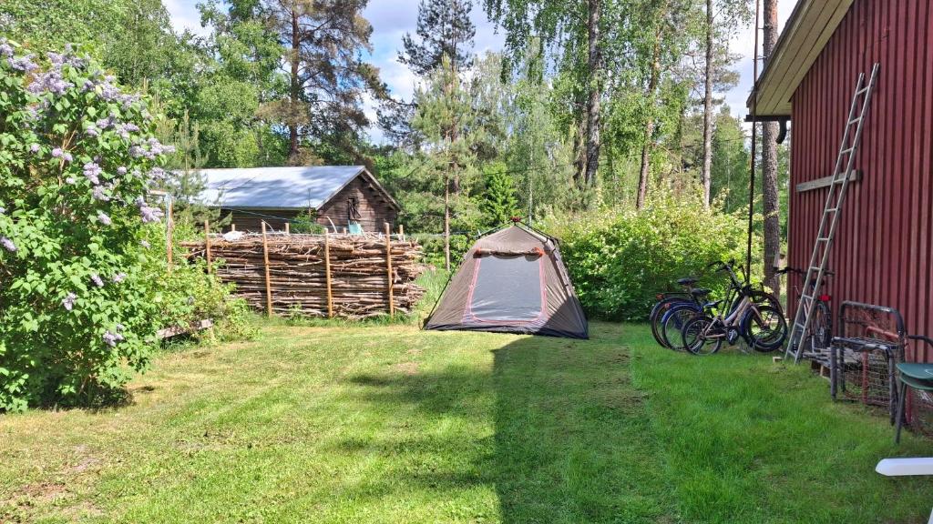 a tent in a yard next to a red barn at B&B RhinoSauna in Vihti