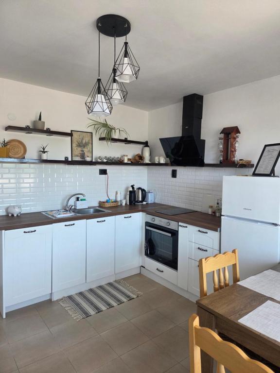 a kitchen with white cabinets and a sink and a table at White House Apartments - Boho in Haskovo