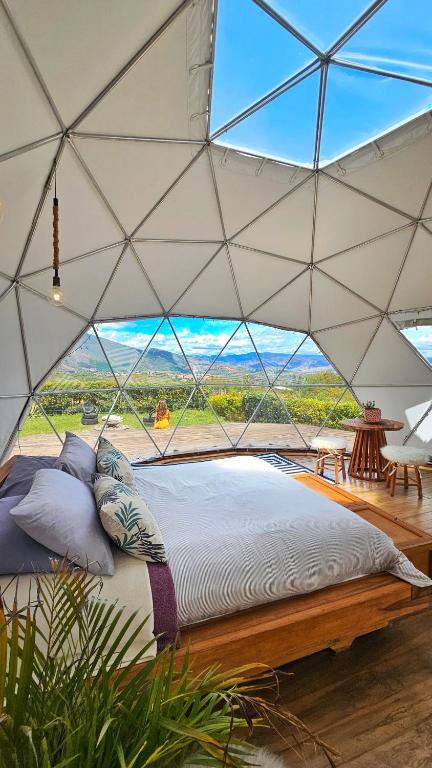 a bed in a tent with a large window at Amatea de Villa de Leyva in Villa de Leyva