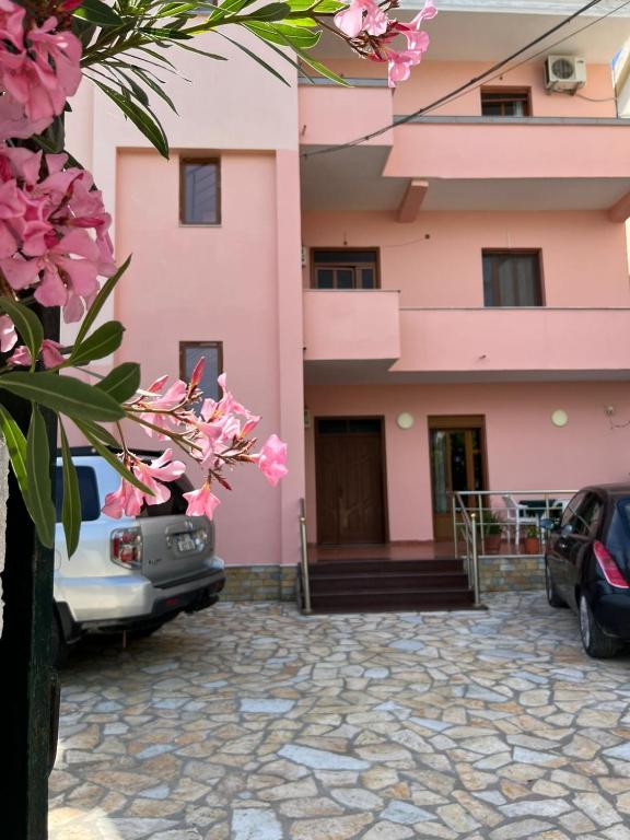 a pink building with cars parked in front of it at Begaj Rooms in Durrës