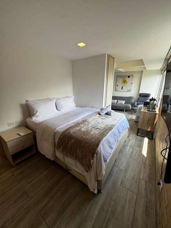 a bedroom with a large bed and wooden floors at 2201 Hermoso apartamento poblado in Medellín