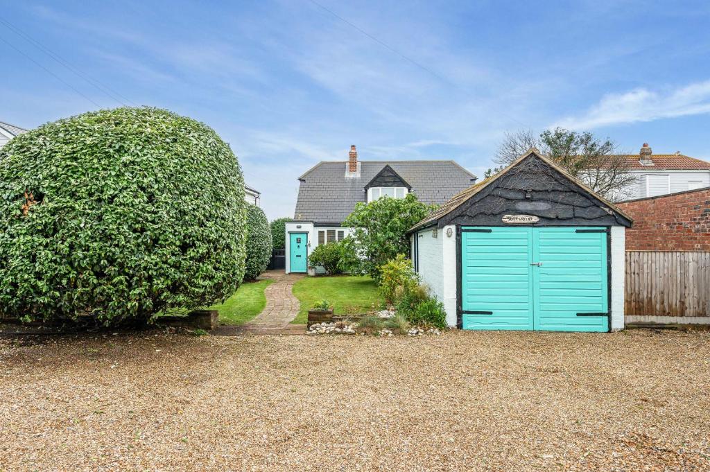 a house with a blue garage in a driveway at Saltwater, East Wittering in East Wittering