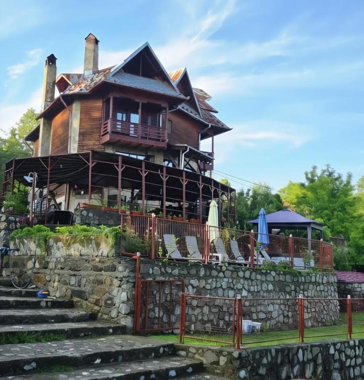 a large house with a stone wall and chairs at Cabana Magdalena in Câmpulung