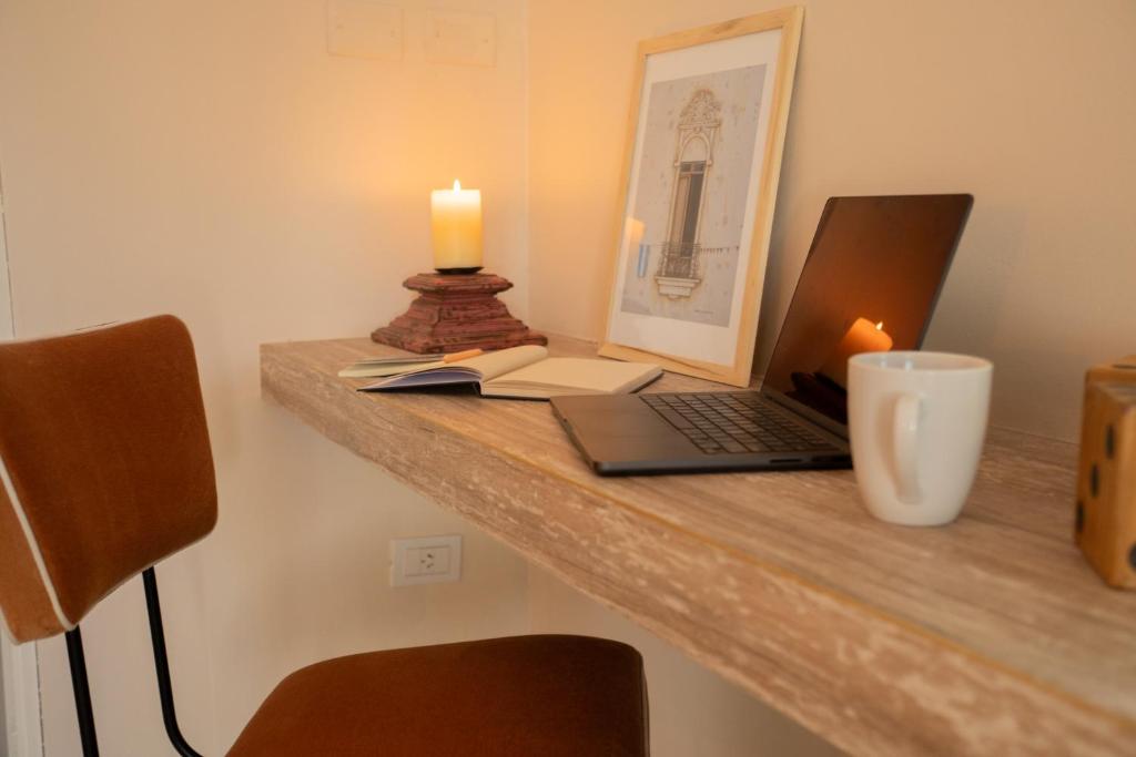 a desk with a laptop computer and a candle on it at Atelier Petit Hotel in Ciudad Lujan de Cuyo