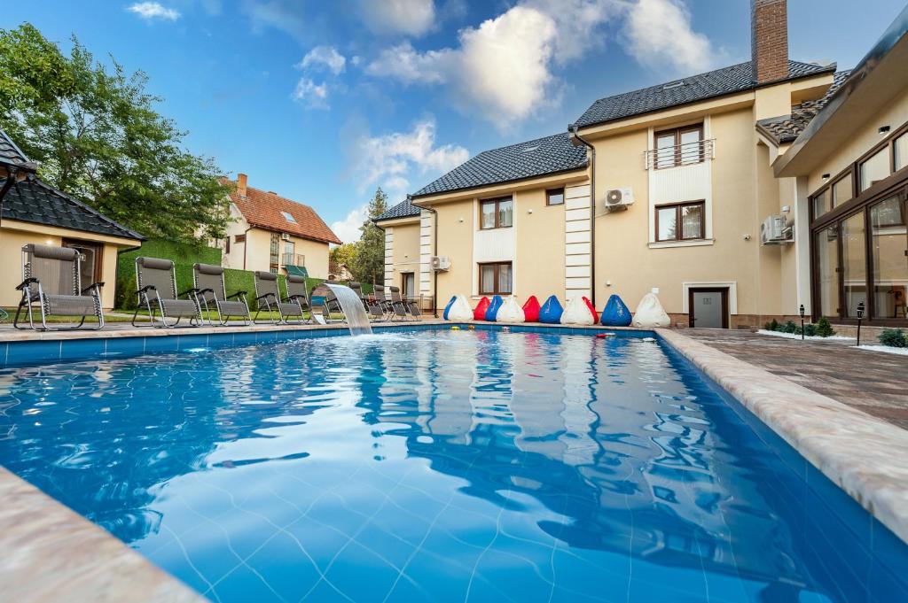 a swimming pool in front of a house at HOTEL Villa Cvijanović - WELLNESS-SPA in Palić