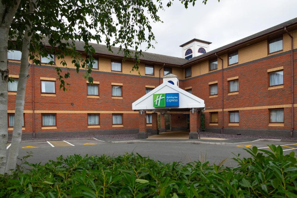a red brick building with a sign in front of it at Holiday Inn Express Exeter East by IHG in Exeter