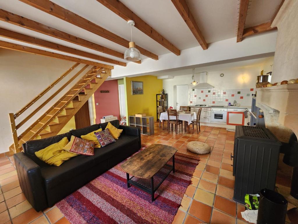 a living room with a black couch and a table at Le Gîte du Moulin in Saint-Maigrin