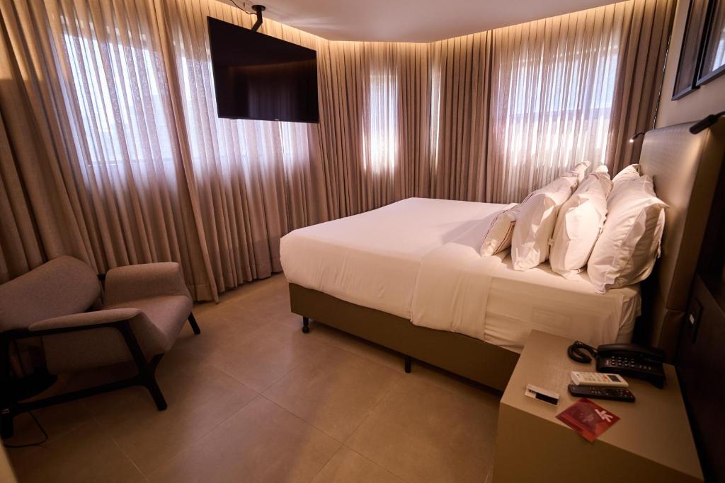 a hotel room with a bed and a chair and a desk at Royal Collection Paulista in São Paulo