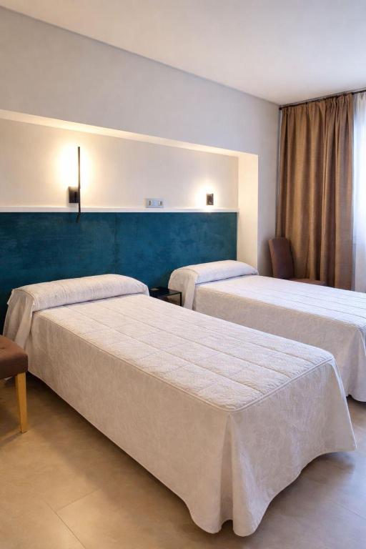 a hotel room with two beds and a blue wall at Pensión Ariz in Basauri