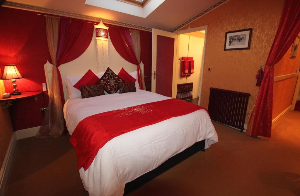 a hotel room with a large bed with red curtains at The PitStop in Bishops Stortford
