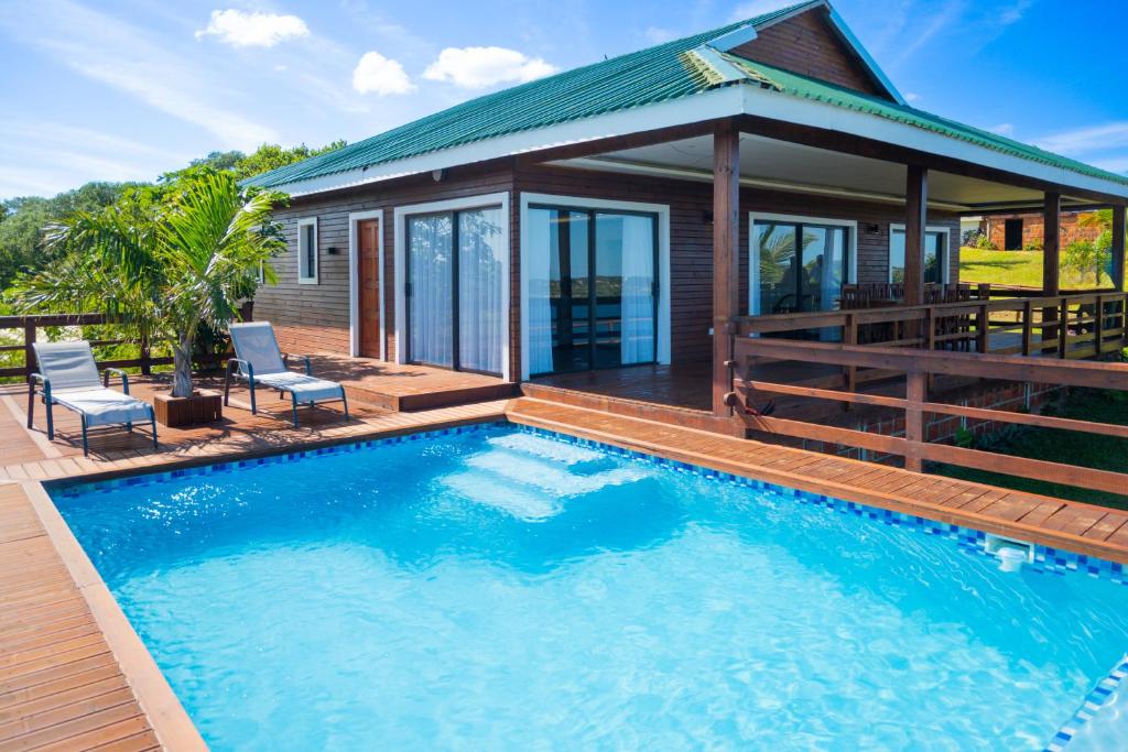 a house with a swimming pool in front of a house at KoKo Beach - Wooden Green House in Vila Praia Do Bilene