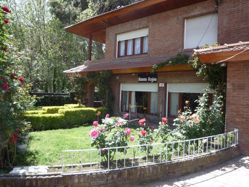 una casa de ladrillo con flores en el patio delantero en Chalet familiar adosado Roses Rojas en Villa Gesell