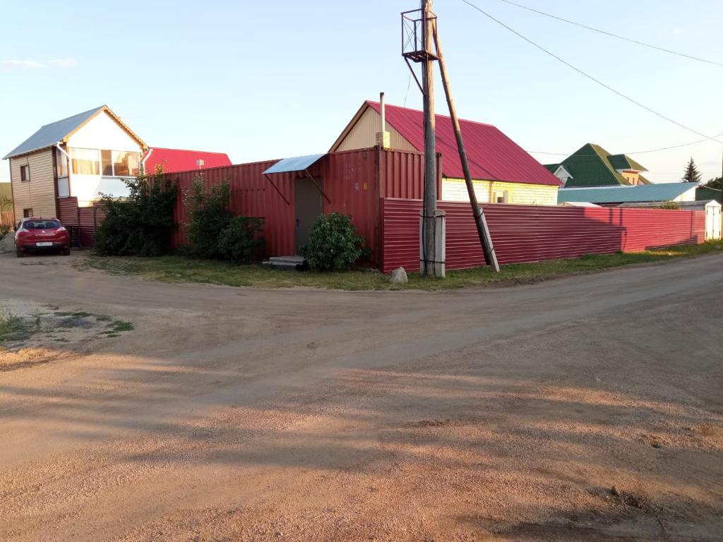 a red barn next to a road with a house at Домики ШАХ in Borovoye