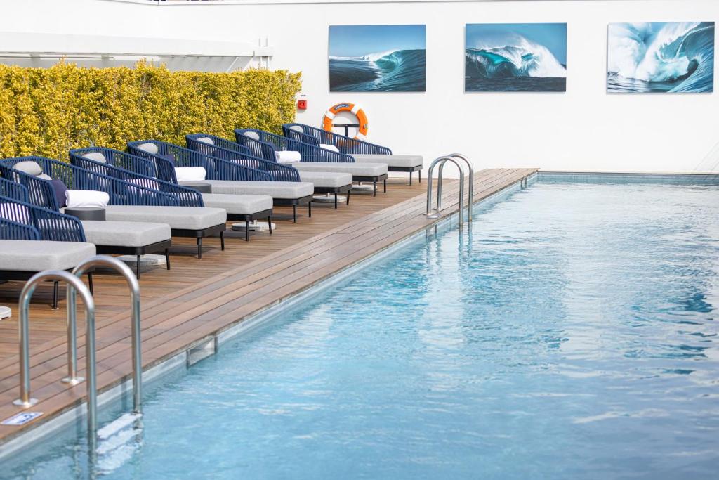 a swimming pool with blue chairs next to the water at Hotel Indigo Cagnes-sur-Mer by IHG in Cagnes-sur-Mer