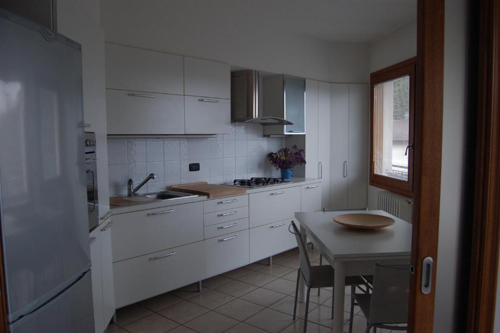 una cucina con armadi bianchi e un tavolo di Appartamento Europa a Fanano