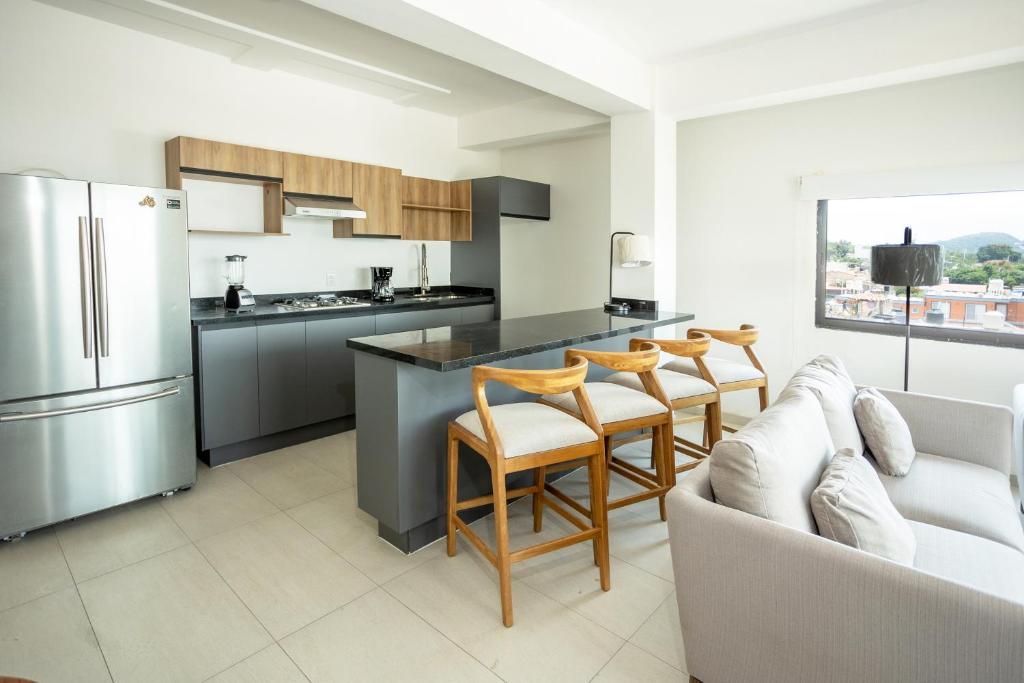 a kitchen with a counter and chairs and a refrigerator at Suites Santa Isabella in Ajijic