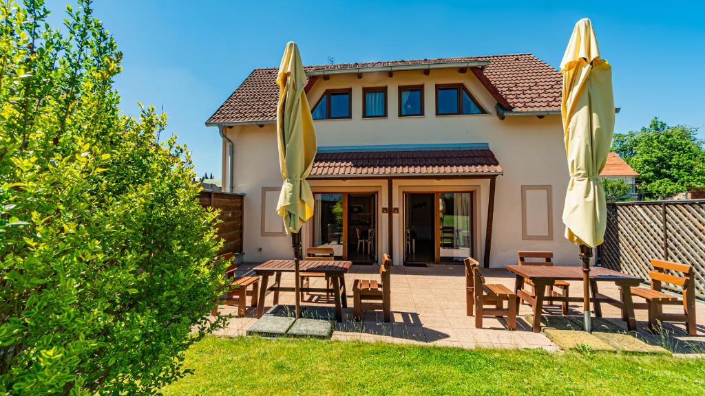 a patio with tables and umbrellas in front of a house at Penzion Adria III in Dobrohoř