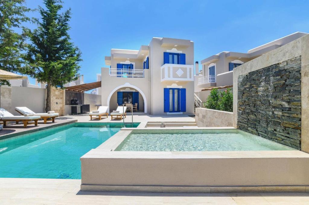 a villa with a swimming pool in front of a house at Villa Kalymnos by Villa Plus in Kolymbia