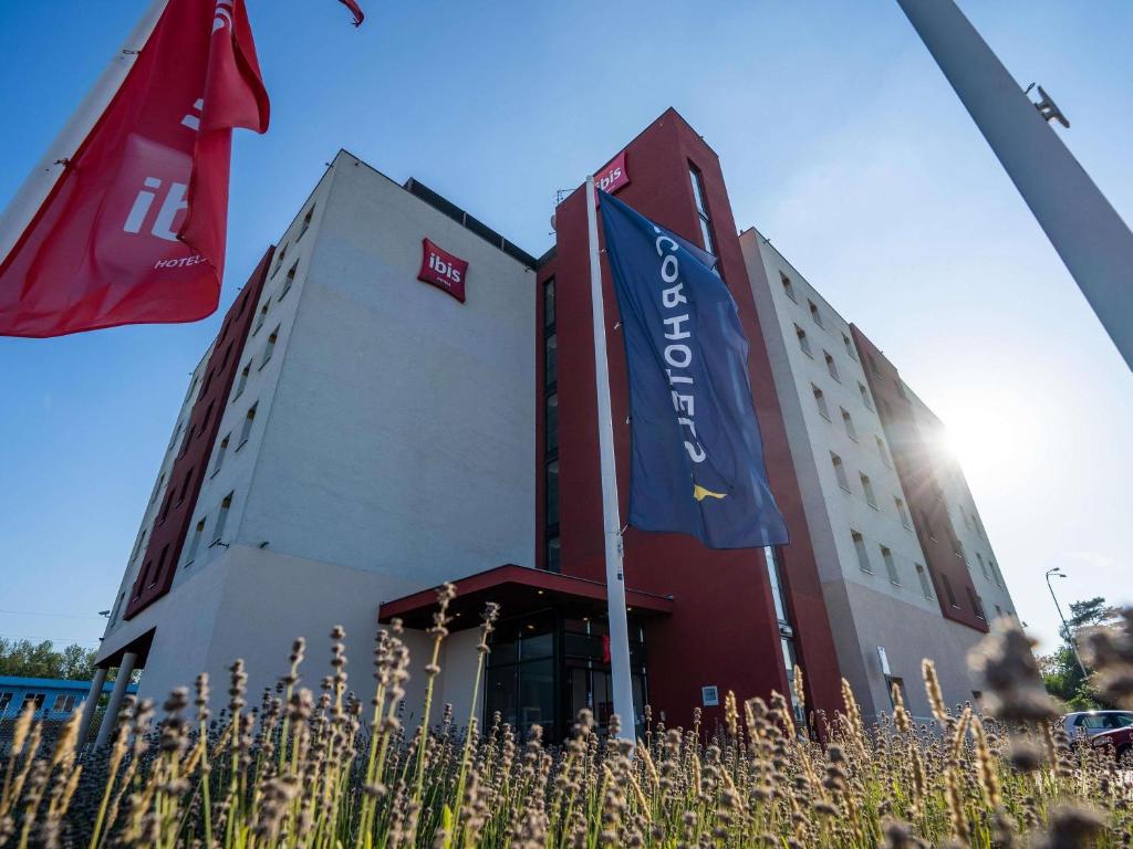 a building with two flags in front of it at Ibis Hotel Plzeň in Pilsen