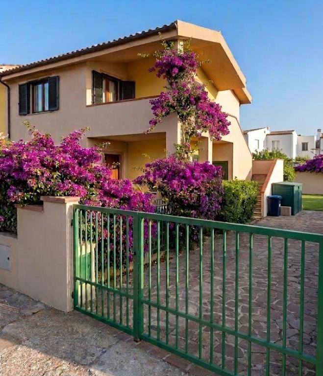 a house with purple flowers in front of a fence at Casa Iole in Budoni